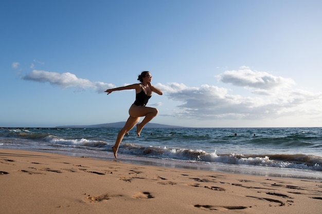 La siluetta corrente della donna funziona sull'esercizio di sport del mare al concetto della spiaggia