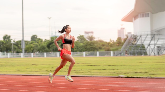 スタジアムのトラックで晴れた朝に走っている女性