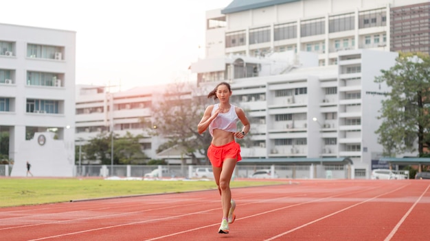 화창한 아침에 경기장 트랙에서 달리는 여성