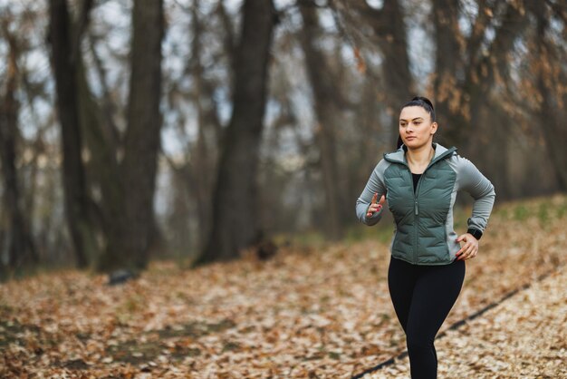 写真 秋 の 葉っぱ の 中 で 森 を 走っ て いる 女性