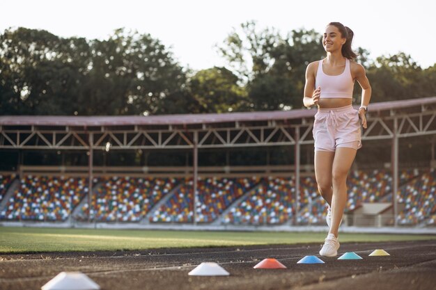 Woman running on track at the stadium using barriers