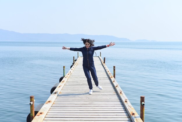 Woman running on a wooden pier by the Japanese sea