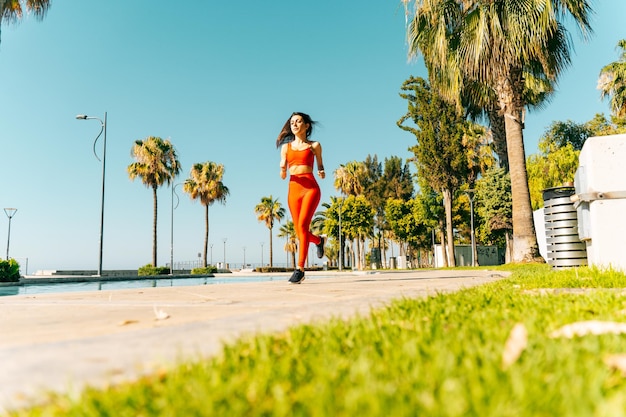 Woman runs and does fitness exercises outdoor in a sunny day