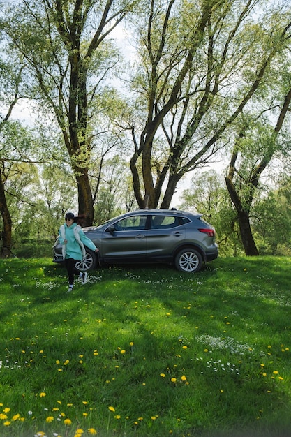 женщина бежит от припаркованной машины на зеленом газоне в природе