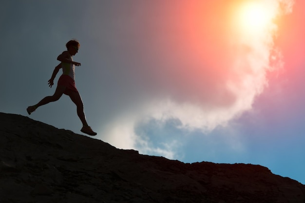 Woman runs on the ridge with colorful sun