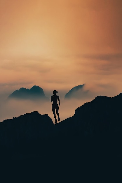 Woman runs in silhouette through the mountains