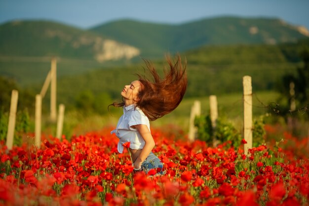 ケシのフィールドの牧草地の田園風景の女性。