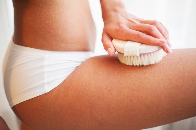 Woman's arm holding dry brush for cellulite treatment