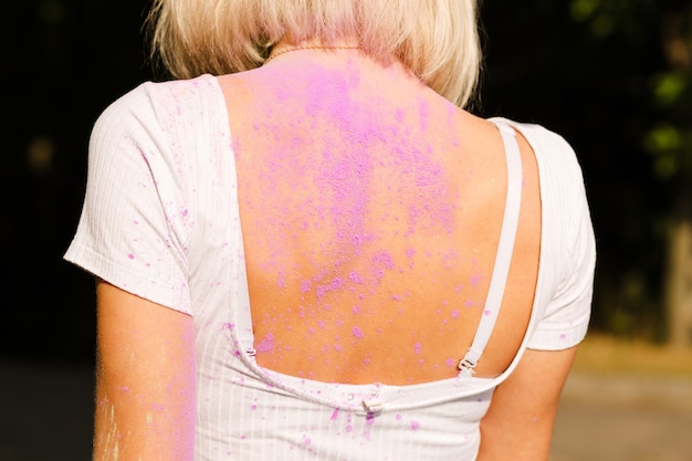 Спина женщины покрыта сухой розовой пудрой Гулал.