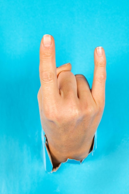 Woman's ear through the torn blue paper. gesture.