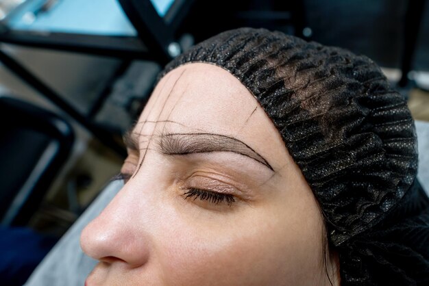 Photo woman's eyebrows with guide lines around the eyebrows to get the exact measurements for the permanent eyebrow makeup procedure