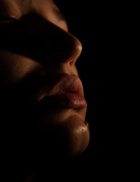 A woman's face is illuminated by a lamp that is on a black background.