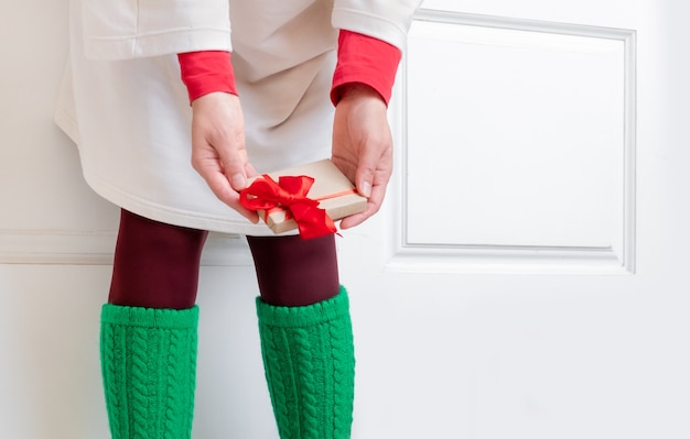 Woman's feet in green Socks stand near the White Door with Gifts