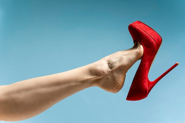 woman's feet wearing red high hills. isolated on blue background