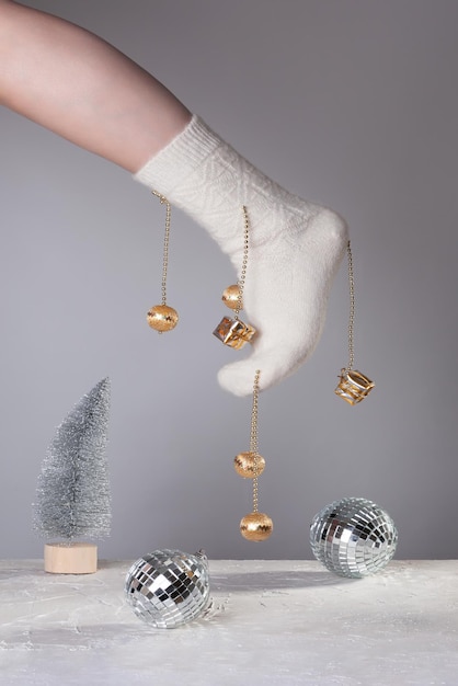 A woman\'s foot in a white sock decorated with christmas toys\
above the stage with a silver artificial christmas tree and a disco\
balls