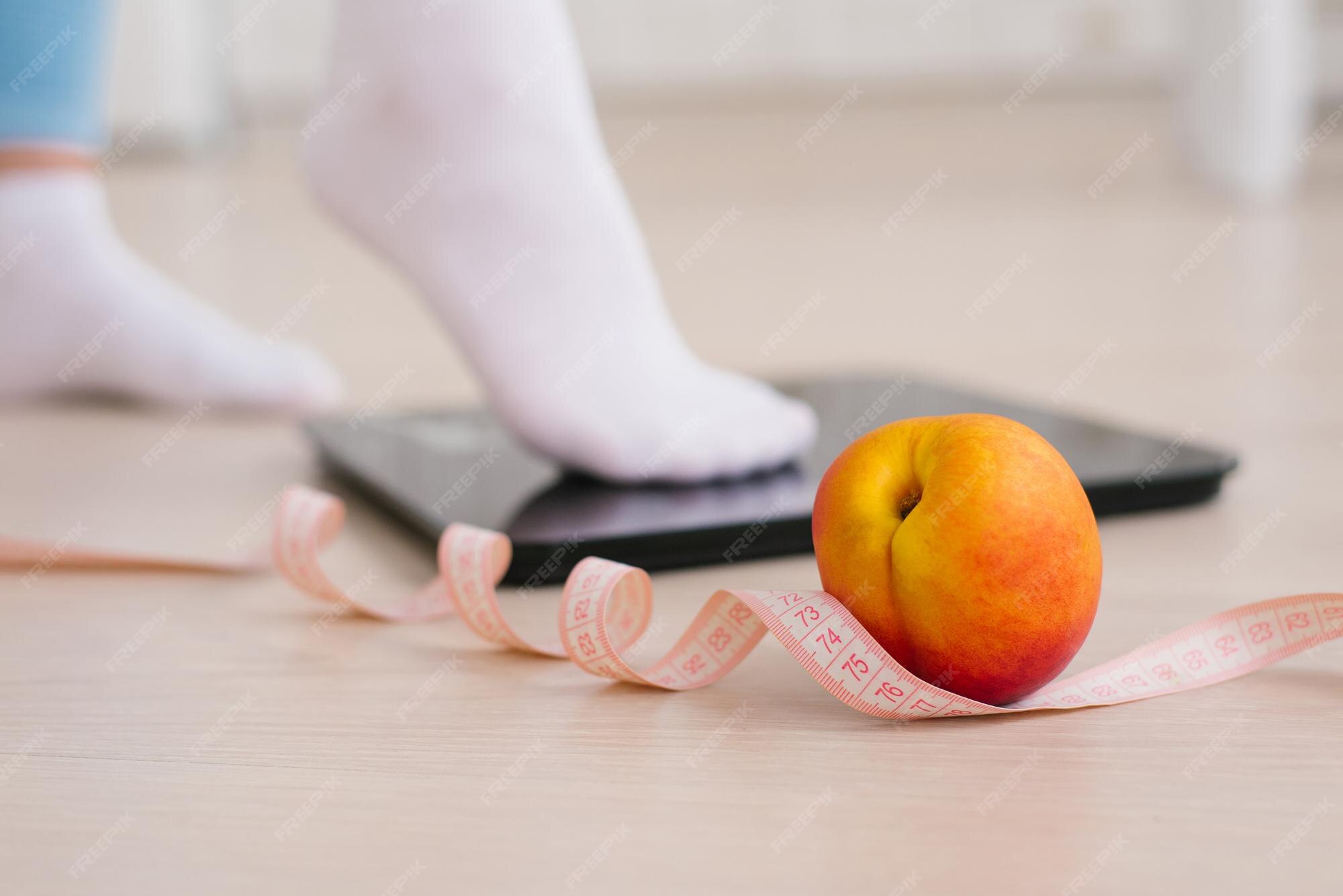 Premium Photo | Woman's foot in white yjcrt stepping on a scale with a  measuring tape and fresh peach fruit the concept of a healthy lifestyle  nutrition and sports