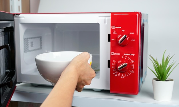 Woman's hand adjusts the temperature with a circular button to warm food from the kitchen microwave.