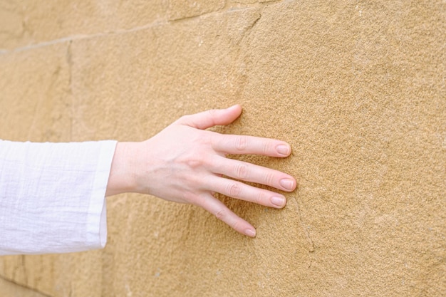 Woman's hand on the background of a yellow brick wall