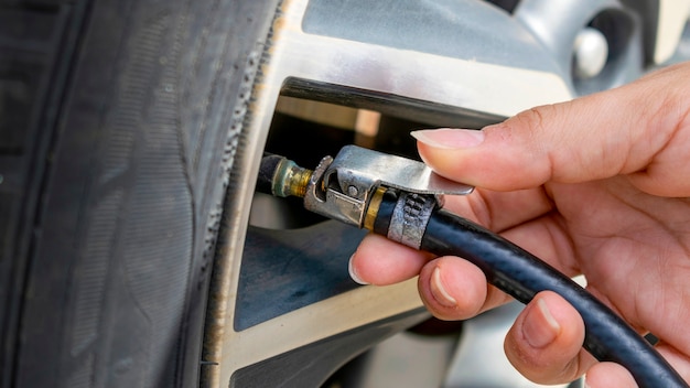 Woman's hand calibrating car tire. preventive vehicle maintenance