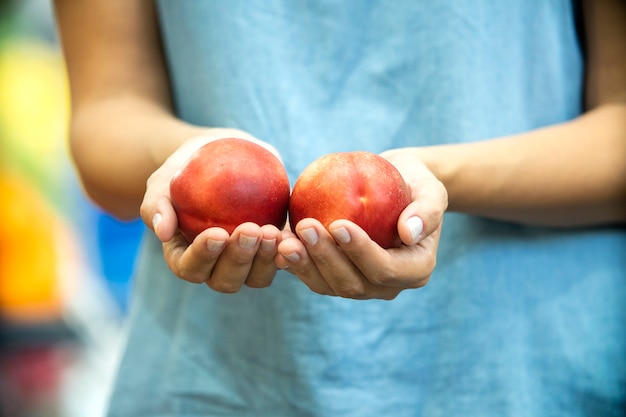 Woman's hand choosing peach in supermarket.