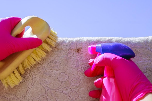 Photo woman's hand cleans the carpet with a brush