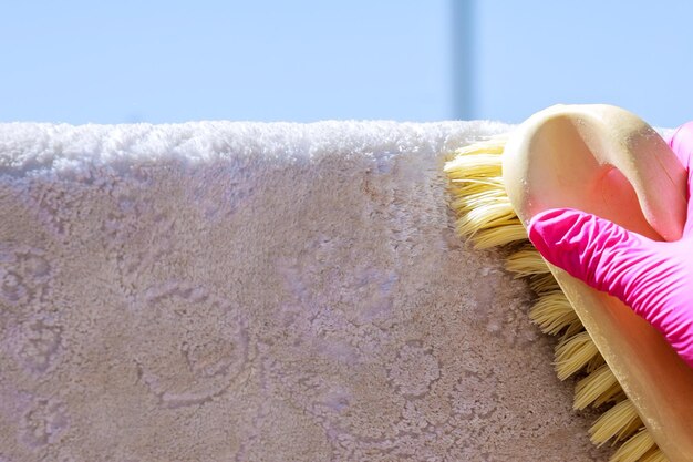 Photo woman's hand cleans the carpet with a brush