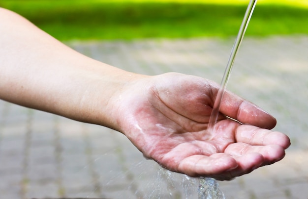 Foto mano della donna sotto l'acqua corrente fredda.