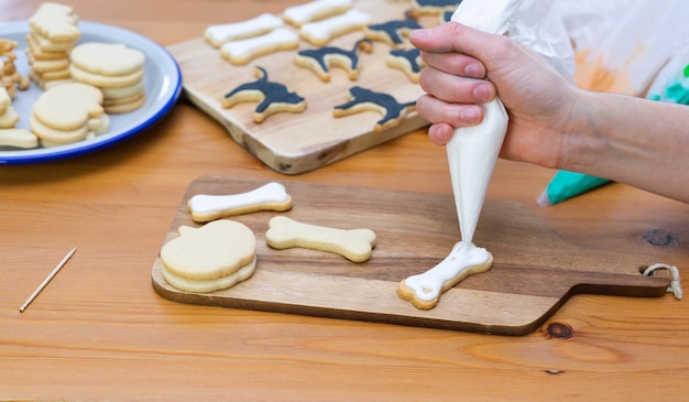 Woman's hand decorating cookies for Halloween with piping bag.