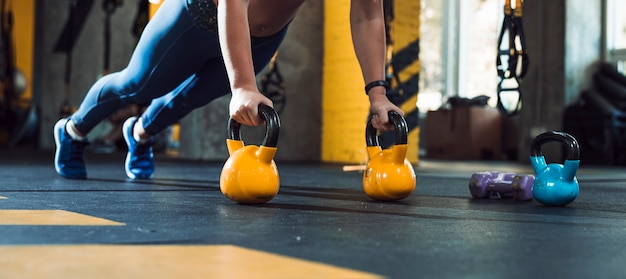 Foto fare della mano della donna spinge aumenta sulla palla del bollitore in palestra