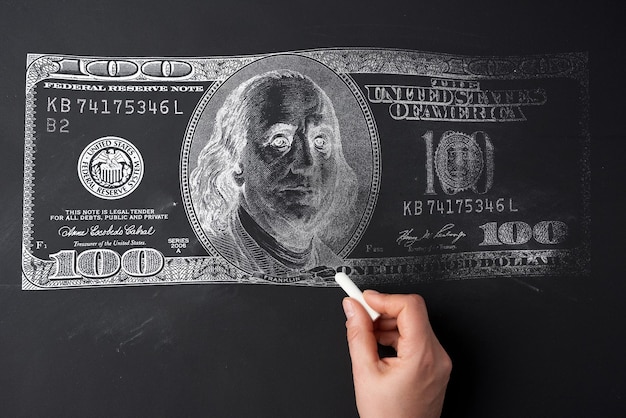 A woman's hand draws a dollar on a black chalk board The concept of inflation rising prices