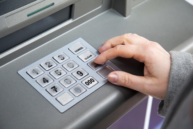 woman's hand enters the pin code into ATM