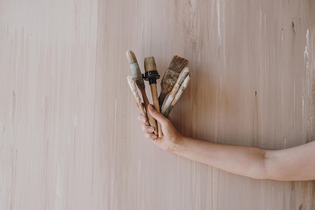 Woman's hand hold paintbrushes on neutral beige background Minimalist art concept