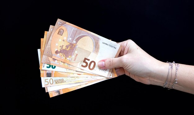 黒の背景に 50 ユーロ紙幣を持っている女性の手