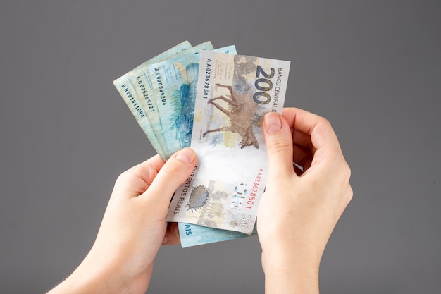 Woman's hand holding Brazilian money notes