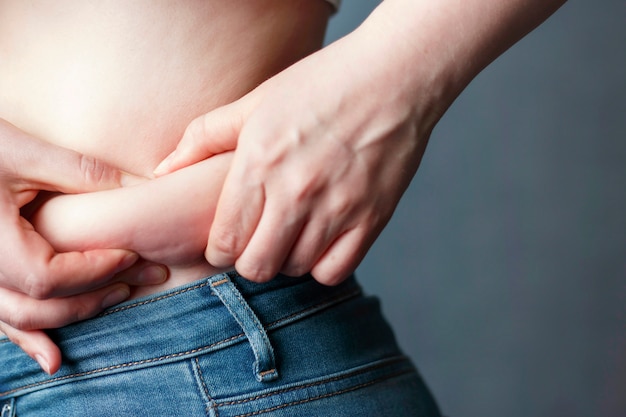 Woman's hand holding excessive belly fat