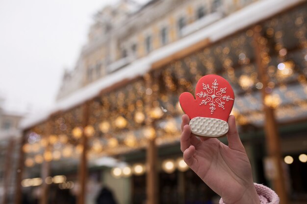 Woman's hand holding gingerbread at the Christmas fair against the background of bokeh