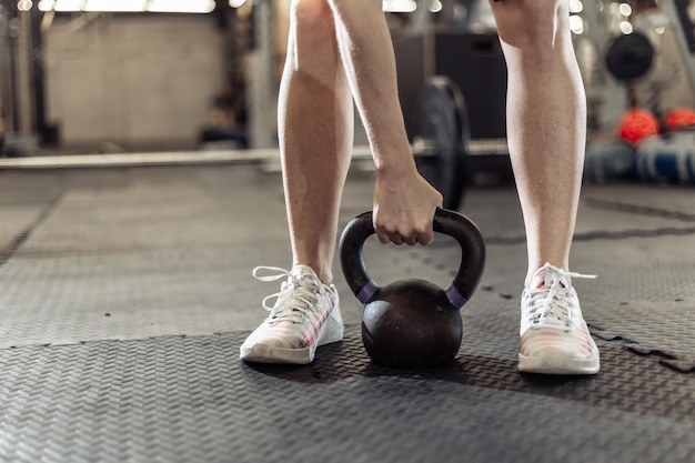 Woman's hand holding a heavy kettlebell in the gym
