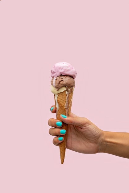 Woman's hand holding an ice cream cone melting in a pink