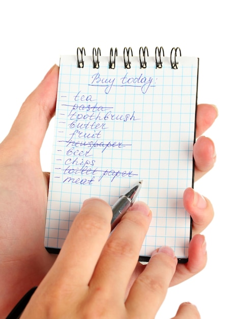 Woman's hand holding a notebook with a shopping list closeup