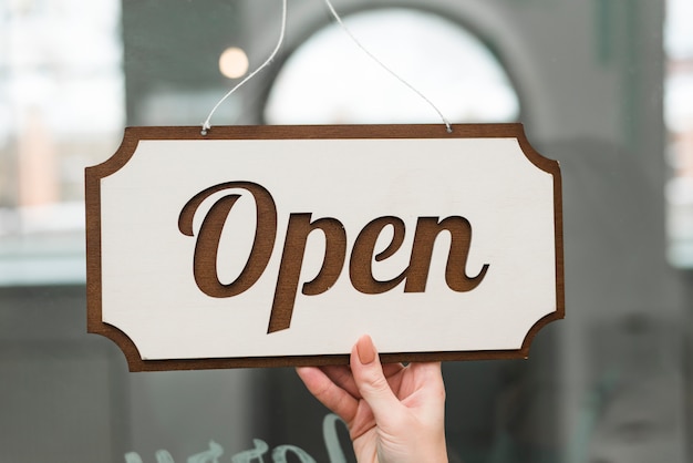 Woman's hand holding opened tag hanging on a glass of storefront