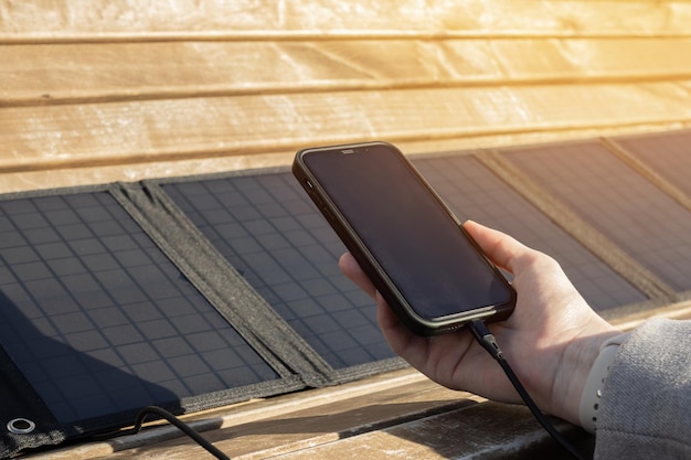 Woman's hand holding a phone connected to a solar panel