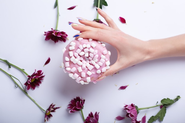 Woman's hand holding a pink donut