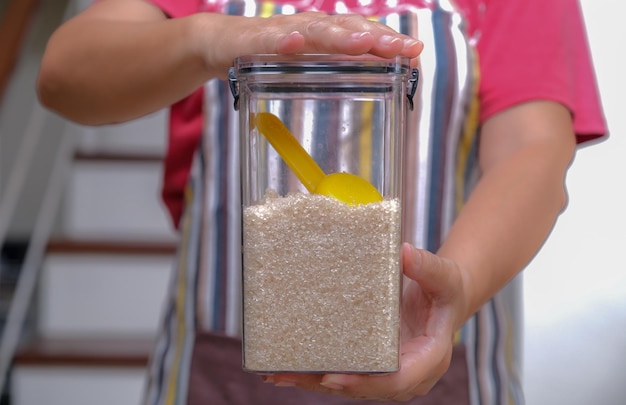 Photo a woman's hand holding a plastic box of white sugar