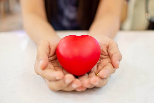 Foto la mano della donna che tiene cuore rosso