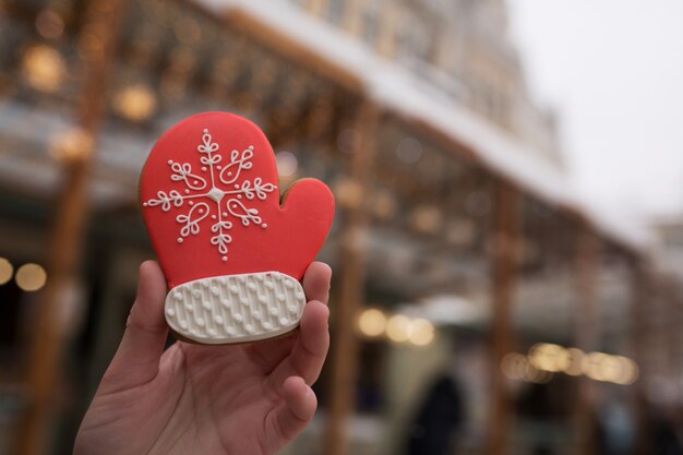 Woman's hand holding small gingerbread at the Christmas fair against the background of bokeh