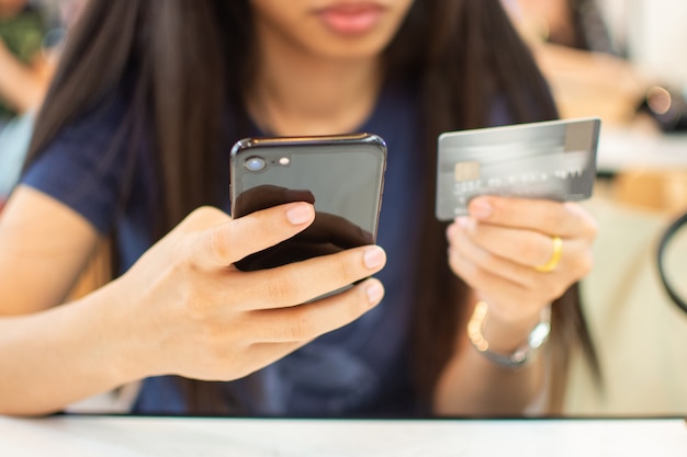 Smart phone della tenuta della mano della donna e carta di credito per il concetto online di compera.