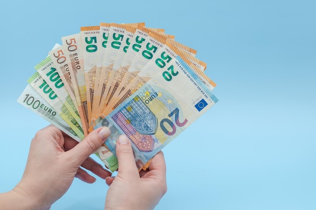 Woman\'s hand holding stack of money euro on blue background\
money business