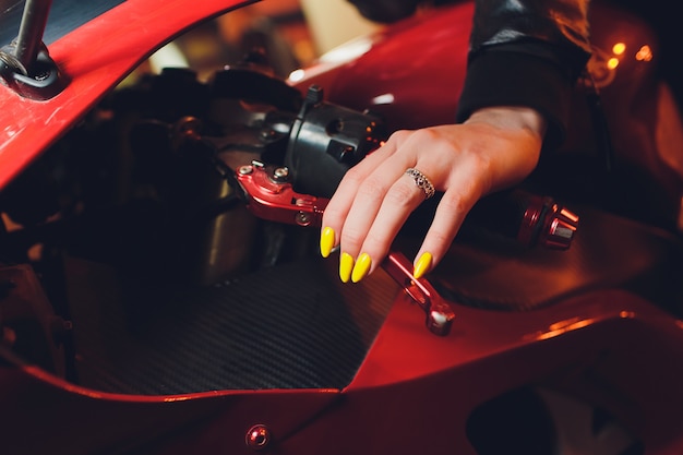 Photo woman's hand holding steering wheel motorcycle yellow manicure.