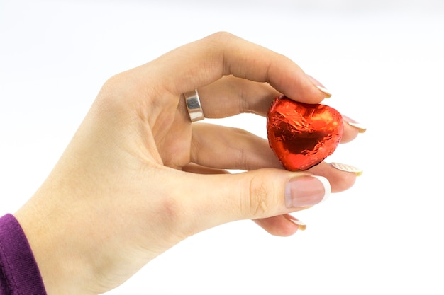 Woman's hand holding sweet red heart on white