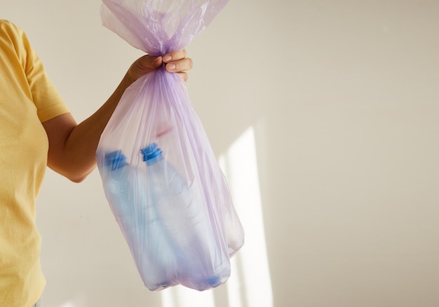 Woman's hand holding a trash bag with plastic bottles